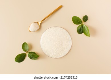 Hydrolyzed collagen powder in a Petri dish and a spoon a beige background. - Shutterstock ID 2174252313