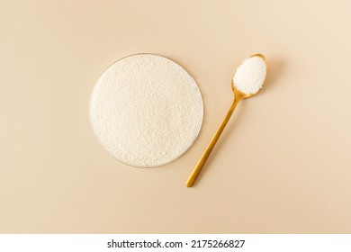 Hydrolyzed collagen powder in a Petri dish and a spoon a beige background. - Shutterstock ID 2175266827