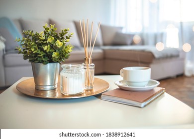 Hygge and aromatherapy concept - Coffee, candles, book and aroma reed diffuser on table at home. Home fragrance in sticks. Air freshener, diffuser and aromatherapy concept 
