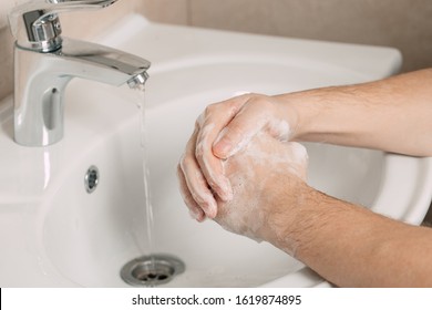 Hygiene concept. Washing hands with soap under the tap with water. handsome male hands and water in the bathroom. - Shutterstock ID 1619874895