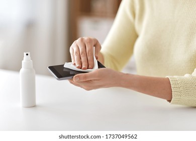 hygiene and disinfection concept - close up of woman hands cleaning smartphone with hand sanitizer and tissue - Powered by Shutterstock