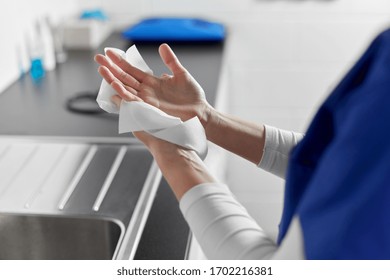 hygiene, health care and safety concept - close up of female doctor or nurse drying hands with paper tissue at hospital - Shutterstock ID 1702216381