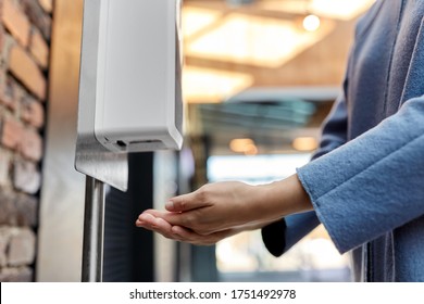 hygiene, health care and safety concept - close up of woman using hand sanitizer from dispenser at shopping mall - Shutterstock ID 1751492978