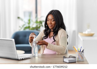 hygiene, health care and safety concept - african american woman using antibacterial hand sanitizer at home office - Powered by Shutterstock