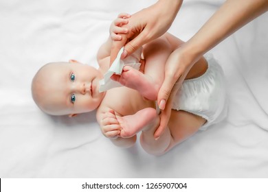 Hygiene - young mom wiping the baby skin body and leg with wet wipes carefully on white background. concept cleaning wipe, pure, clean.