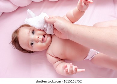 Hygiene - Young Mom Wiping The Baby Skin Body And Face With Wet Wipes Carefully On Pink Background. Concept Cleaning Wipe, Pure, Clean.