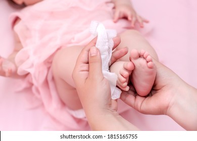 Hygiene - young mom wiping the baby skin body and face with wet wipes carefully on pink background. concept cleaning wipe, pure, clean.
