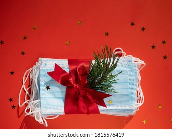 Hygienic face masks as a gift with a red ribbon, Christmas and New Year 2021 decor on a red background with space for text. Holidays self-isolation and coronavirus pandemic concept - Powered by Shutterstock