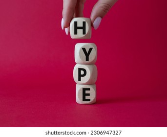 Hype symbol. Concept word Hype on wooden cubes. Businessman hand. Beautiful red background. Business and Hype concept. Copy space.