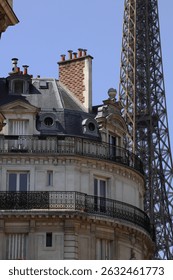 Hyper zoomed in photo with multi-story building with traditional Parisian design elements with the Eiffel Tower subtly appearing in the background