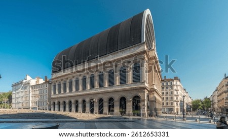 Hyperlapse of Lyon's opera house featuring neoclassical architecture combined with a modern glass dome roof. A historical and touristic landmark with statues under blue sky. Side view timelapse