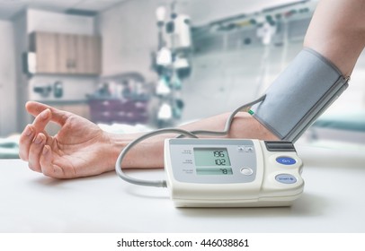 Hypertension Concept. Man Is Measuring Blood Pressure With Monitor In Hospital.