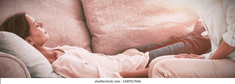 Hypnotherapist holding pendulum by patient on sofa at home - Powered by Shutterstock