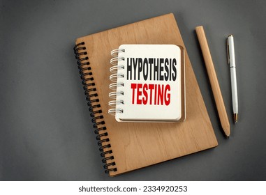 Hypothesis testing text on a notebook with pen and pencil on grey background