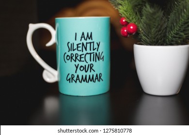 "I am silently correcting your grammar" coffee mug for comedy and education purposes. Turquoise mug on black ground with cozy background.