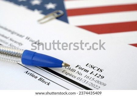 I-129 Petition for a nonimmigrant worker blank form lies on United States flag with blue pen from Department of Homeland Security close up