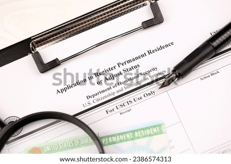 I-485 Application to register permanent residence or adjust status form and green card from dv-lottery on A4 tablet, lies on office table with pen and magnifying glass close up