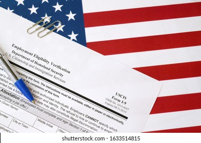 I-9 Employment Eligibility Verification blank form lies on United States flag with blue pen from Department of Homeland Security