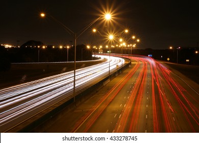 I-95 At Boca Raton, Florida, Facing South At Night Near Glades Road Off-Ramp With Lights Overhead, Time Exposure Making Passing Red And White Car Lights With Orange Flashing Blnkers Creating Streaks