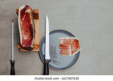Iberian ham on a ham stand with knife and plate.