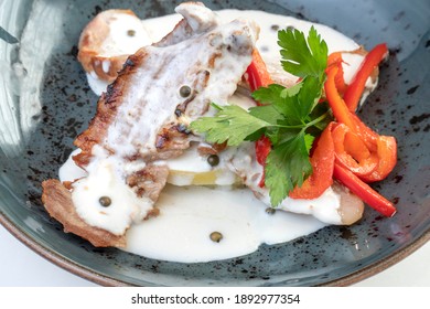 Iberian Secret With Pepper Sauce, Parsley And Vegetables, On A Dark Blue Plate