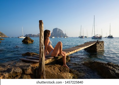 Ibiza cala d Hort girl on pier sunset Es Vedra islet Balearic Islands