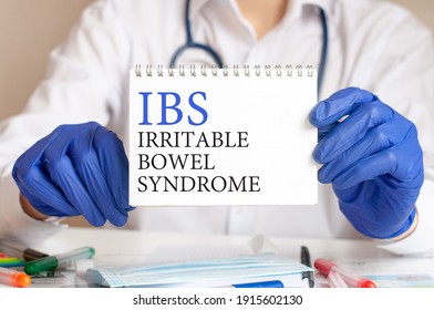 IBS Card In Hands Of Medical Doctor. Doctor's Hands In Blue Gloves Holding A Sheet Of Paper With Text IBS - Short For Irritable Bowel Syndrome, Medical Concept.