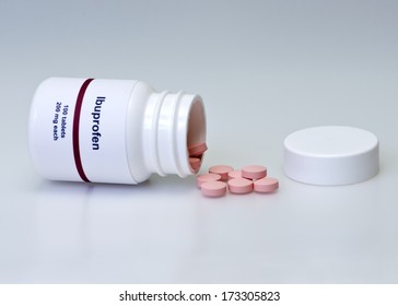 Ibuprofen bottle and pink tablets. 