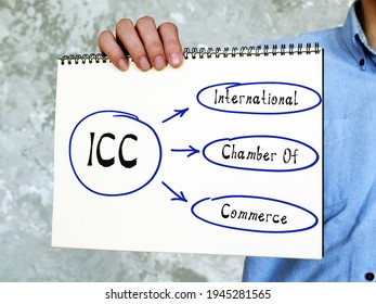  ICC International Chamber Of Commerce Inscription. Young Businessman Dressed In Blue Shirt And Tie Holding Blank Sheet Of Paper 
