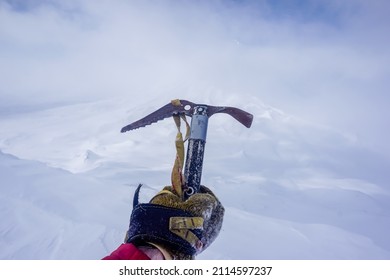Ice ax in hand on the background of snow-capped mountains