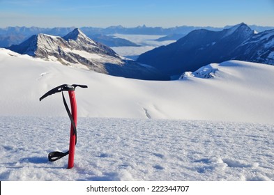 Ice ax stuck in the snow high in the mountains above the glacier - Powered by Shutterstock