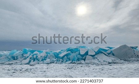 Ice blocks on the beach. Winter landscape with ice hummocks sparkling in the sun on the lake, the sea. High ice piles and blue ice hummocks. Selective focus.