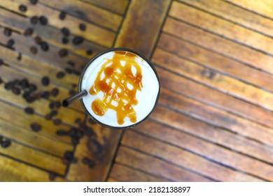 Ice Caramel Latte With Coffee Beans Isolated On Wooden Table Top View