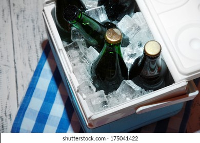 Ice Chest Full Of Drinks In Bottles On Color Napkin, On Wooden Background