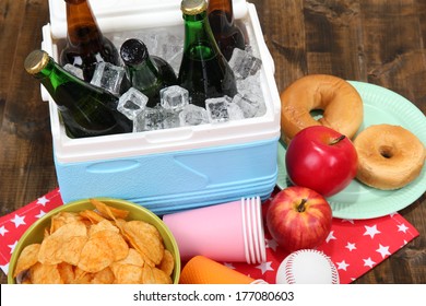 Ice Chest Full Of Drinks In Bottles On Color Napkin, On Wooden Background