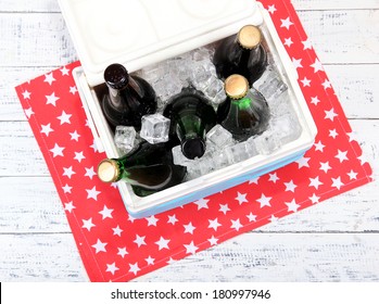 Ice Chest Full Of Drinks In Bottles On Color Napkin, On Wooden Background