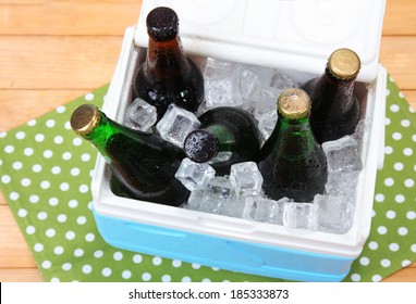 Ice Chest Full Of Drinks In Bottles On Color Napkin, On Wooden Background