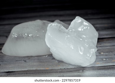 Ice chunks of thick solid pieces of frozen water isolated on wooden background, selective focus of Frosted ice pieces that could be used in refreshments, juices, drinks and many other uses