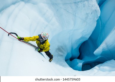 Ice Climber Ascending Out Of A Deep Hole On The Matanuska Glacier In Alaska. Technical Mountaineering In The Alpine Environment And Wilderness. Vertical Climbing.