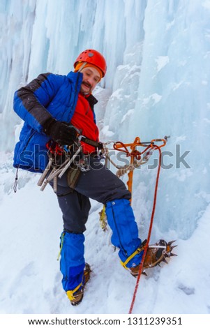 ice climber is fixed on the vertical surface of the glacier with safety anchor