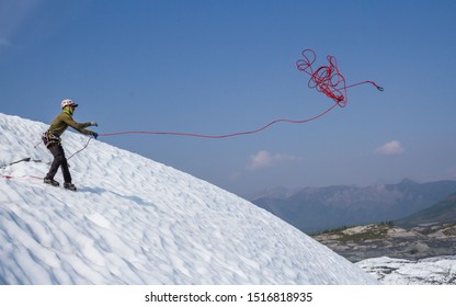 Ice Climbing Guide Tosses A Climbing Rope Down A Slope To Climbers Below Waiting To Ascend.