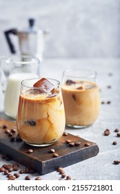 Ice coffee in glass. Ice coffee served in glass with coffee ice cubes and milk cream on table.