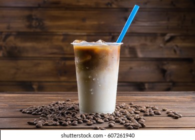 Ice Coffee With Milk In Takeaway Cup And Coffee Beans On Wooden Background