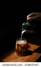 Ice Coffee On A Black Table With Cream Being Poured Into It Showing The Texture And Refreshing Look Of The Drink