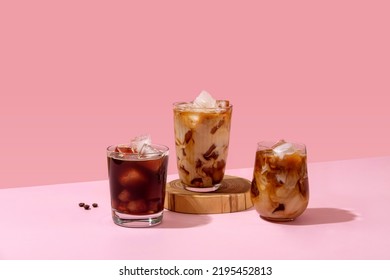 Ice coffee in a tall glass with cream poured over and coffee beans. Set with different types of coffee drinks on a pink table. - Shutterstock ID 2195452813