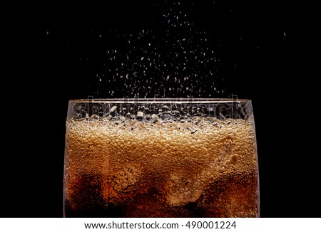 Ice cola with splashing CO bubbles. Drink with ice, closeup, fizzing, fizz.