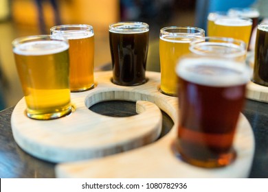 An ice cold foamy craft beer flight is displayed in a variety of small glasses at a brewer and bar. - Powered by Shutterstock