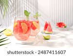 Ice cold homemade lemonade or cocktail with mint, watermelon and fruit, a recipe for a refreshing summer drink. Two glasses with fruit drink on sunny table, detox diet and weight loss concept,