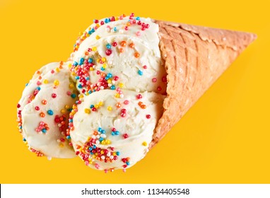 ice cream balls with colored sugar sprinkles in a Waffle Cone on a yellow Background. Vanilla ice cream in a waffle cone.