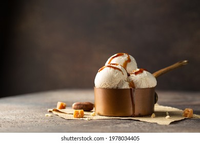 Ice cream balls in a cooper saucepan with caramel on brown background.Close up of sweet desert in freeze motion.
